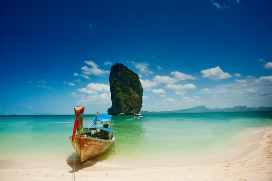 A traditional Thai boat on a stunning beach in Thailand with a beautiful sea and sky background