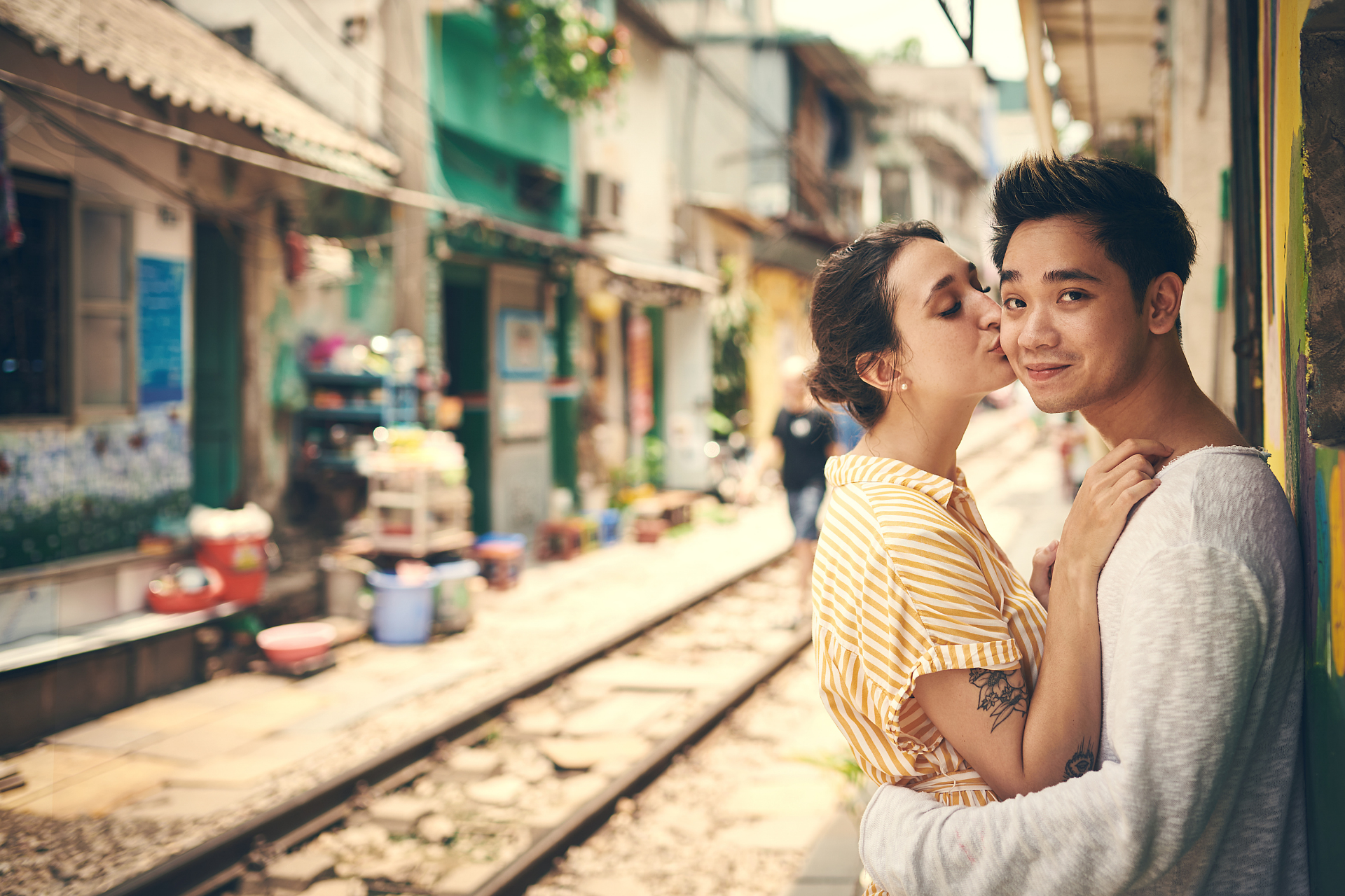 Hanoi railway tracks through shopping area with a couple looking at the camera