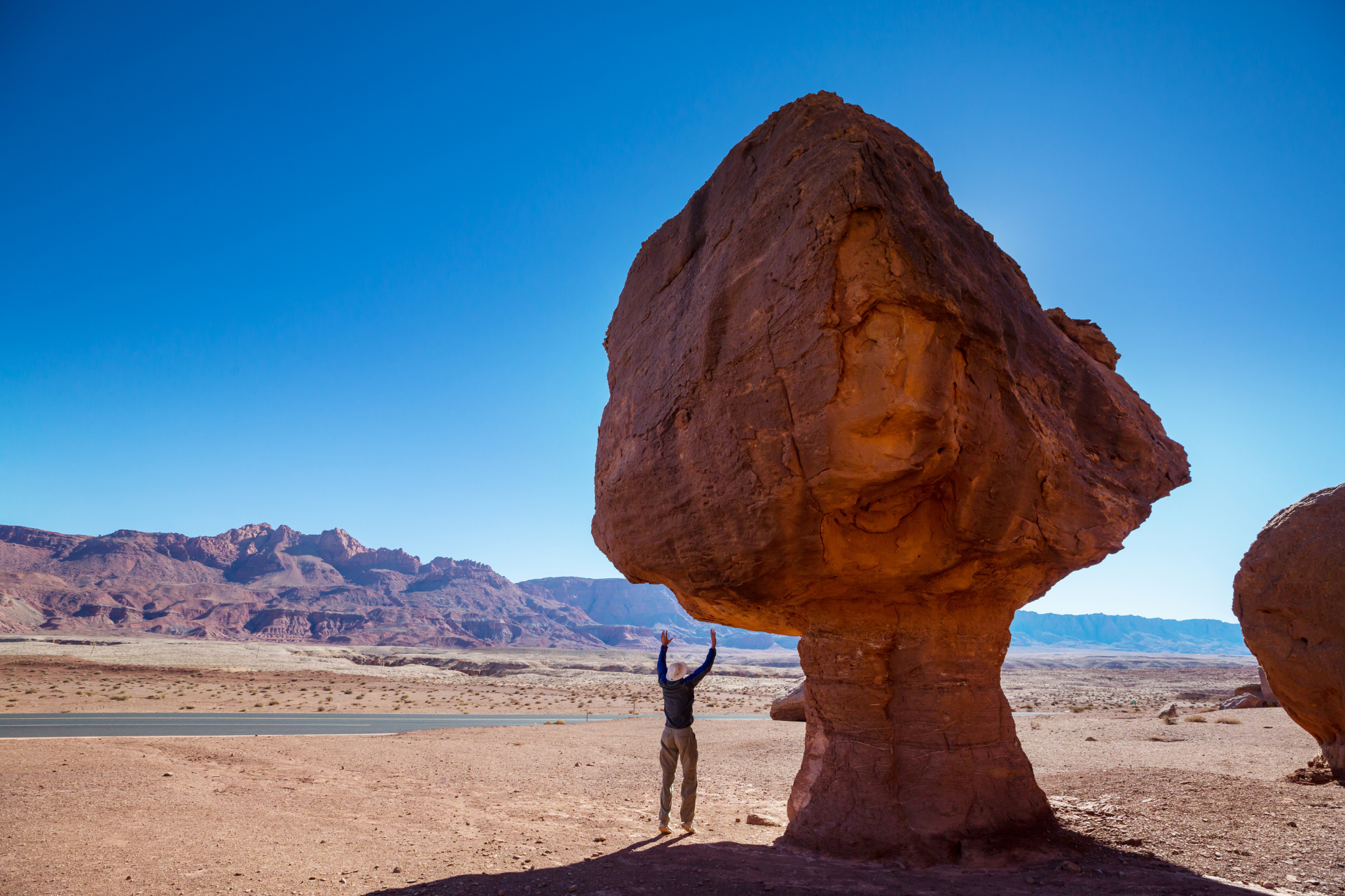 A rock formation in Petra Jordan with a man standing beneath it