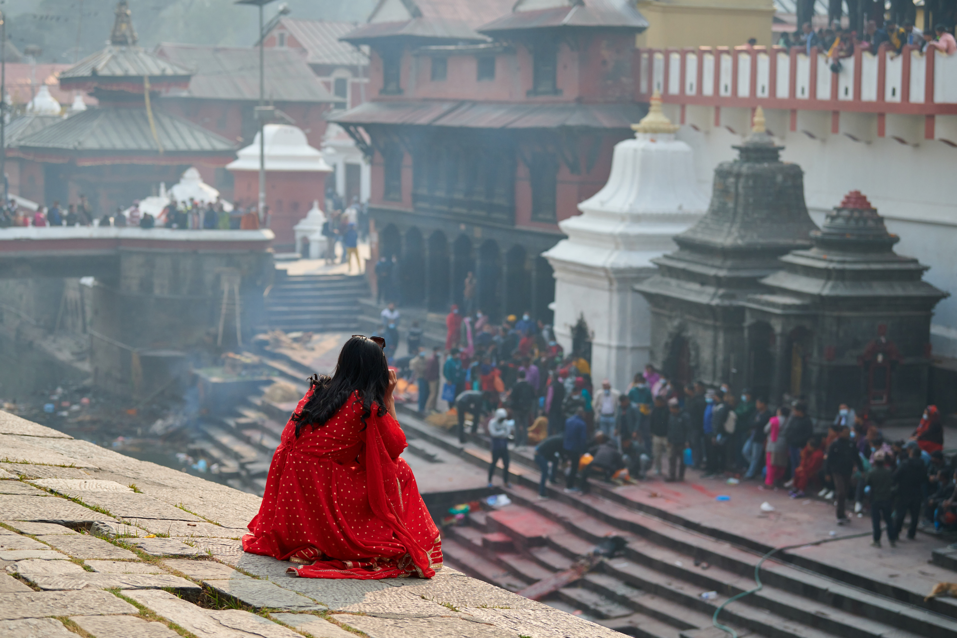 back view of woman in red sari watching mournful
